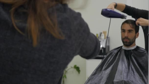 Профессиональный парикмахер сушит волосы в салоне красоты. Молодой мужчина и парикмахер. close up — стоковое видео