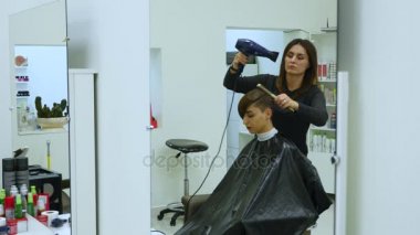 Genç bir kadın bir Kuaför koltukta oturur: Kuaför saç şekillendirme yapar. Genç sarışın kadın şık bir saç modeli yapmak için güzellik salonuna geldi