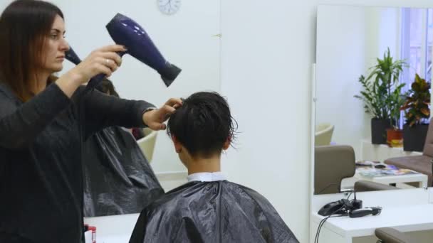 Парикмахерская сушка и расчесывание волос женщины в парикмахерской — стоковое видео
