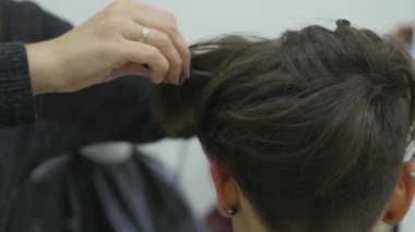 Genç bir kadın bir Kuaför koltukta oturur: Kuaför saç şekillendirme yapar. Genç sarışın kadın şık bir saç modeli yapmak için güzellik salonuna geldi