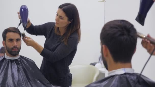 プロの美容師が美容室で髪を乾燥します。若い男性のお客様と女性の理容室。クローズ アップ — ストック動画