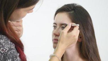 Profesyonel makyaj sanatçısı özel fırça kullanarak modeli göz için göz farı uygulamak. Doğal makyaj salonda. Güzellik, makyaj ve moda kavramı