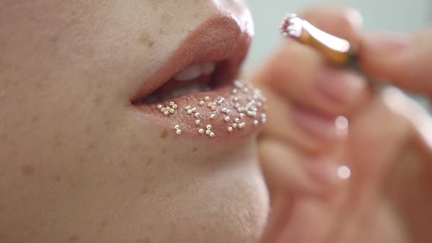 Maquillador pone confeti en los labios. confeti en los labios, maquillaje hermoso y colorante brillante de labios — Vídeo de stock