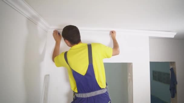 Werknemer corrigeert de plint aan het plafond — Stockvideo