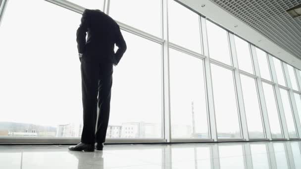 Man come and stand at full height, olhar para fora da janela do terminal do aeroporto — Vídeo de Stock