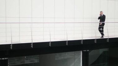 İşadamı yürümek ve telefon iş merkezi balkonda konuşmak