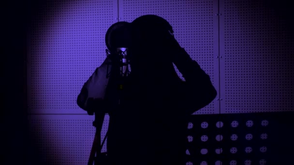 En ung kvinna sjunger en låt i en mikrofon i en inspelningsstudio i Neon ljus — Stockvideo