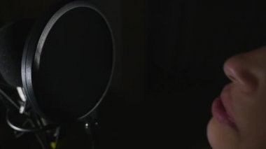 Genç güzel kız şarkı söylüyor. Genç şarkıcı bir mikrofona şarkı. Portre ve şarkıcı kapatın. Kayıt stüdyosu. Kayıt stüdyosu şarkıcılar