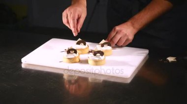 Şef tatlı pasta süsle. Son rötuşları close-up. Adam pudra eller. İle krem çikolata cupcakes üzerine asmak. Yavaşça ve dikkatlice konfeksiyon ile dekore edilmiş pudra