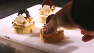 Şef tatlı pasta süsle. Son rötuşları close-up. Adam pudra eller. İle krem çikolata cupcakes üzerine asmak. Yavaşça ve dikkatlice konfeksiyon ile dekore edilmiş pudra