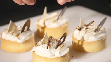 Şef tatlı pasta süsle. Son rötuşları close-up. Adam pudra eller. İle krem çikolata cupcakes üzerine asmak. Yavaşça ve dikkatlice konfeksiyon ile dekore edilmiş pudra