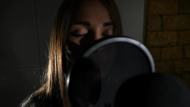Όμορφη κοπέλα που τραγουδάει. Νεαρός τραγουδιστής τραγουδά σε ένα μικρόφωνο. Πορτρέτο κοντινό πλάνο του τραγουδιστή. Στούντιο ηχογράφησης. Καταγραφή σε οι τραγουδιστές στούντιο — Αρχείο Βίντεο