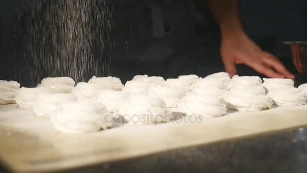 Mãos masculinas polvilhando com açúcar de confeiteiro um zephyr usando peneira. Confeiteiro polvilha açúcar em pó em marshmallow — Vídeo de Stock