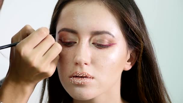 Makeupartist målar en ung flicka ögonbryn mörka professionell färg. slowmotion — Stockvideo