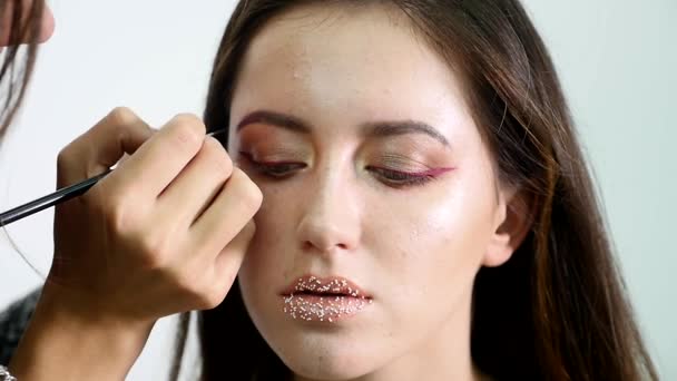 Makeupartist målar en ung flicka ögonbryn mörka professionell färg. slowmotion — Stockvideo