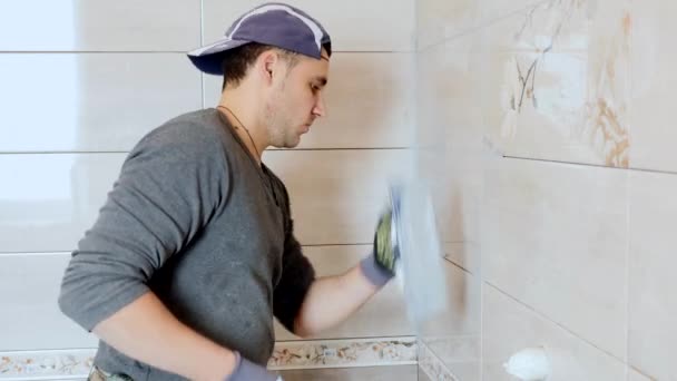 Uomo mettendo cuciture di piastrelle beige sul muro. Chiudi, 4K — Video Stock