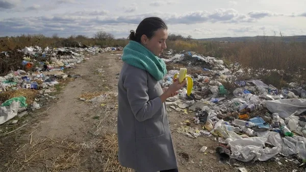 Young woman walking through a garbage dump — Stock Photo, Image