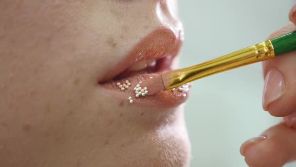 Make-up artiest zet confetti op de lippen. confetti op de lippen, mooie make-up en lichte colorer van lippen — Stockvideo