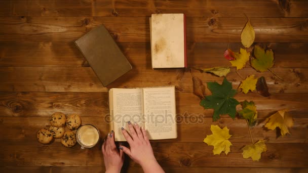 秋季概念顶视图。书, 枫叶, 烤旧木桌。女人在书页上滚动 — 图库视频影像