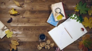Sonbahar konsepti üstten görünüm. Kitaplar, akçaağaç yaprakları, eski ahşap tabloda çay. Not defterinde yazma kadın