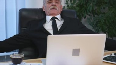 Eski işadamı eğildi geri onun ofis koltuğu, o gülümseme ve hayal