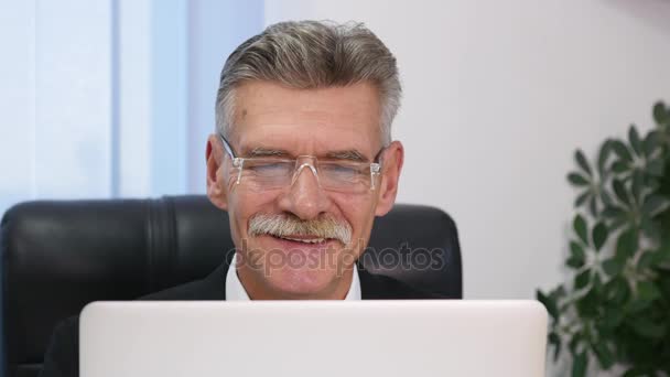 Hombre de negocios de edad avanzada que trabaja con la computadora en la oficina moderna — Vídeo de stock