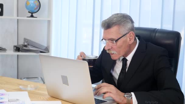 Zakenman drinkt koffie tijdens het kijken naar de laptop scherm — Stockvideo