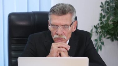 yorgun eski işadamı modern ofisindeki bir bilgisayarla çalışma