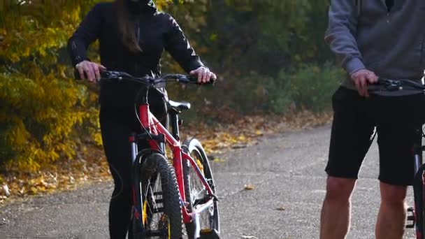 Attractive couple walking with bicycles in the autumn park — Stock Video