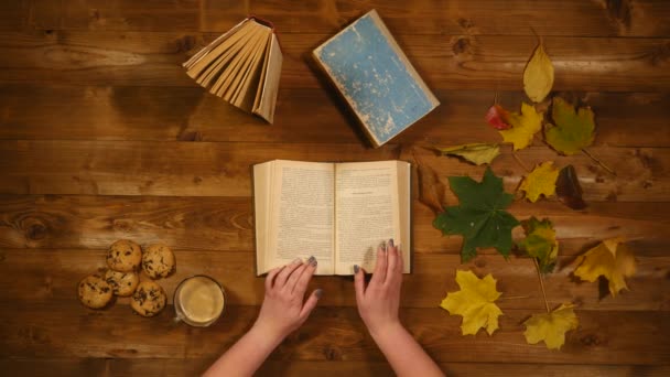 Otoño concepto vista superior. Libros, hojas de arce, té en la vieja mesa de madera. Mujer escribiendo notas en el cuaderno — Vídeos de Stock