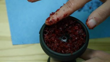 Bir nargile için bir kapta parmak ile tütün tesviye. Tütün yapmak yuvarlak delik. El nargile kase kokulu sulu kırmızı tütün bırakır. Bir nargile 4k hazırlanması