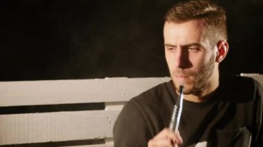 Genç adam bir nargile siyah arka plan üzerine yalnız içiyor