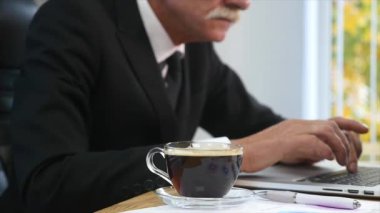 Dizüstü bilgisayar ekranı izlerken işadamı içecekler kahve