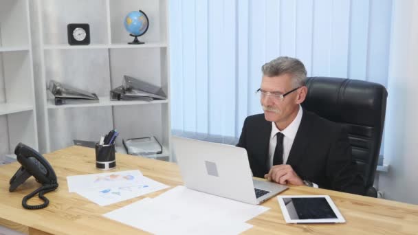 Oudere zakenman werken met computer in moderne kantoren — Stockvideo