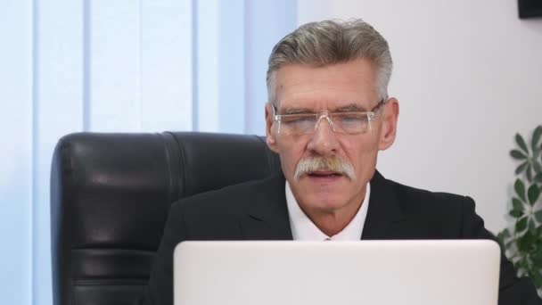 Hombre de negocios de edad avanzada que trabaja con la computadora en la oficina moderna — Vídeos de Stock