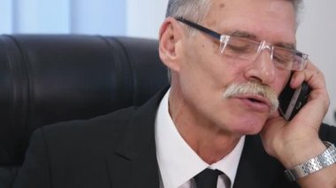 Kıdemli ofis beyaz smartphone ile konuşuyor. yakın çekim