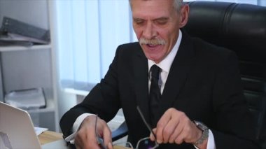 yorgun eski işadamı modern ofisindeki bir bilgisayarla çalışma