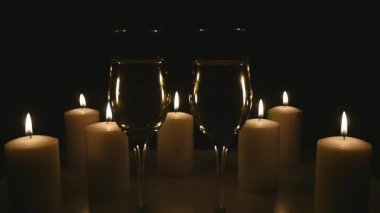 İki bardak şampanya siyah arka plan üzerine mumlar ile