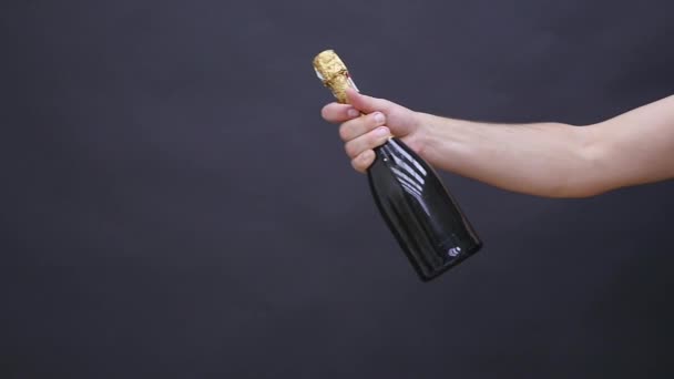 Mans hand med en flaska champagne på en mörk bakgrund — Stockvideo