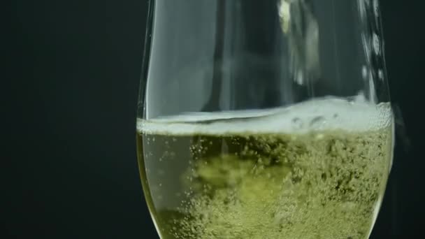 Champagne with bubbles poured into a glass on black background — Stock Video