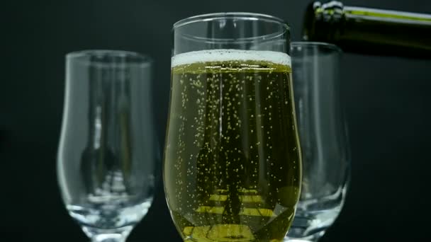 Champagne with bubbles poured into a glass on black background — Stock Video