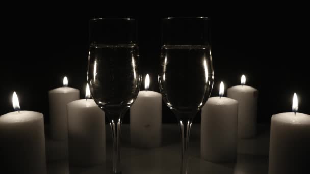 Twee glazen champagne met kaarsen op zwarte achtergrond — Stockvideo