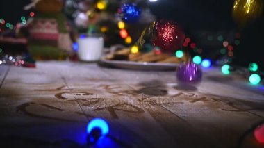 Ahşap kahverengi masa Noel şeyleri ve çelenk ile dekore edilmiştir. Bir bardak süt ve çerezleri Noel masaya bir tabak