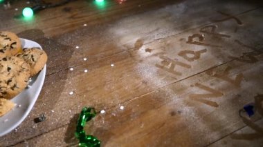 Ahşap kahverengi masa Noel şeyleri ve çelenk ile dekore edilmiştir. Bir bardak süt ve çerezleri Noel masaya bir tabak