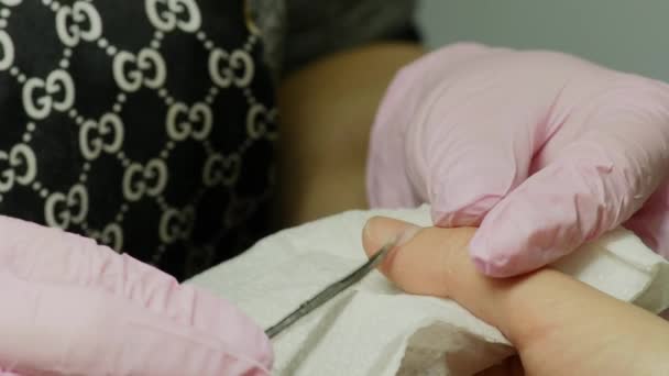 Primer plano de una mujer en un salón de belleza recibiendo una manicura por un esteticista con lima de uñas. Mujer haciéndose manicura de uñas. Lima de esteticista uñas a un cliente — Vídeo de stock