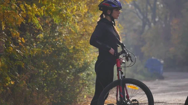 Nahaufnahme einer jungen Frau auf einem Fahrrad im Herbstpark. Zeitlupe — Stockfoto