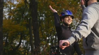 mutlu çift ormanda bisiklet üzerinde bir dağ asfalt yolda birbirimizi bir beşlik vererek kask ile gider