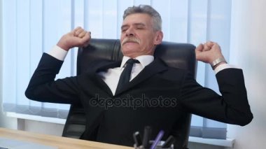 Eski işadamı eğildi geri onun ofis koltuğu, o gülümseme ve hayal