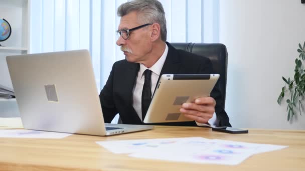 Oudere zakenman werken met computer in moderne kantoren — Stockvideo