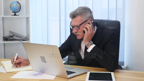 Hombre mayor habla con teléfono inteligente blanco en la oficina — Vídeo de stock